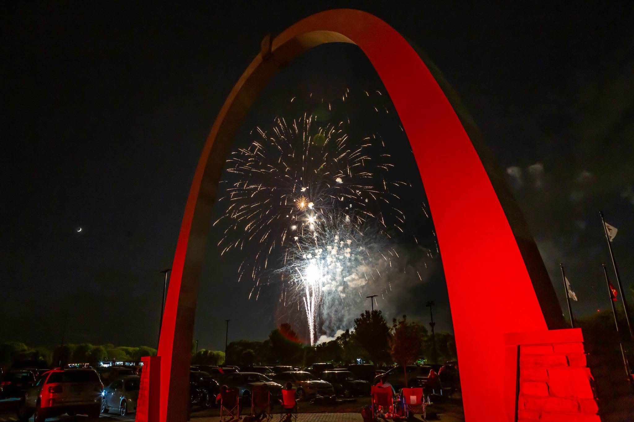 fireworks going off under a arch with red backlighting